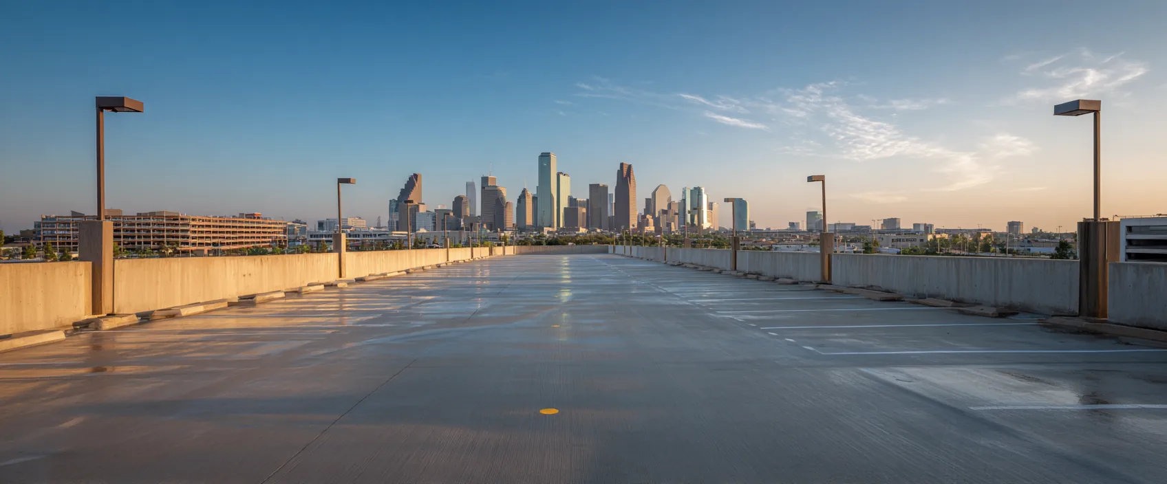 An empty top-level parking deck at golden hour, a city skyline on the horizon